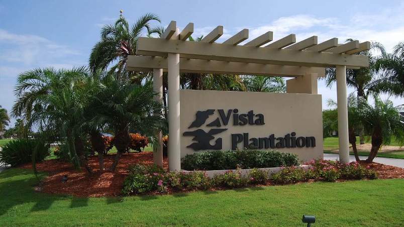 032 - Entrance sign of Vista Plantation with landscaped garden and a pergola structure under a blue sky_